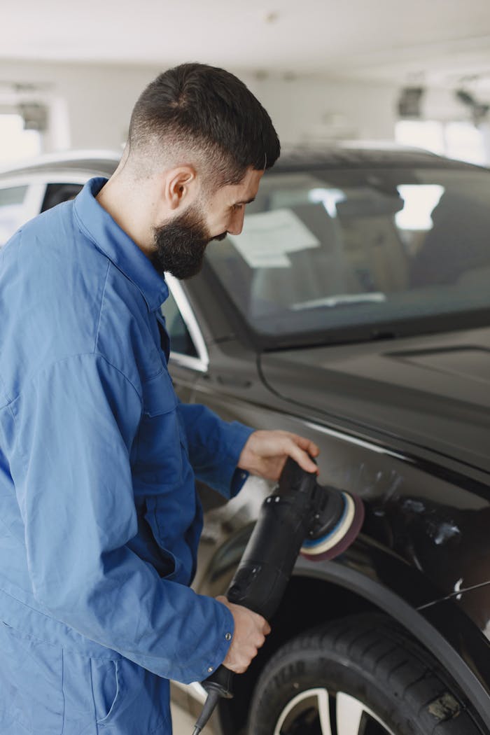 A Man Holding a Polishing Tool on the Car Body